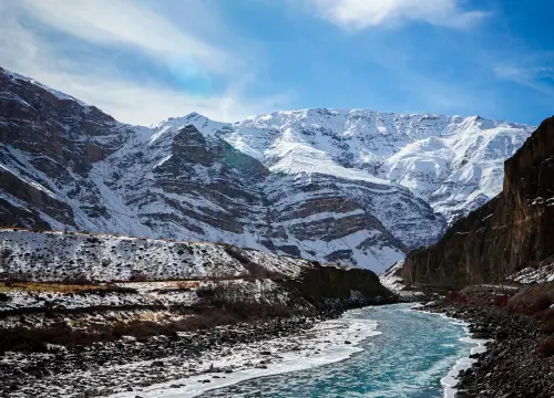 vertical-shot-frozen-river-with-snow-covered-mountains-background